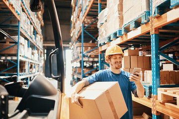 Young male warehouse worker carrying a box
