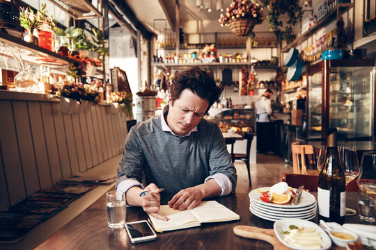 Focused male restaurant owner managing business finances and inventory in cozy bistro