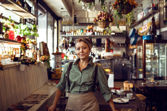 Smiling portrait of a middle aged caucasian female waitress or owner of a small family restaurant in the city