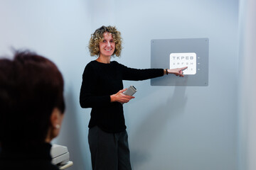 Oculist checking vision to patient projecting numbers and letters on a wall.
