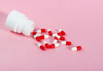 Red and white medicinal tablets on pink background.