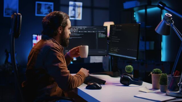 Computer scientist drinking cup of coffee while developing code on PC using java programming languages. IT admin brainstorming ways of fixing database errors, enjoying hot beverage, camera B