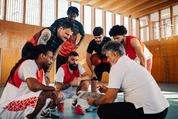 Basketball coach working on game plan with his interracial team.