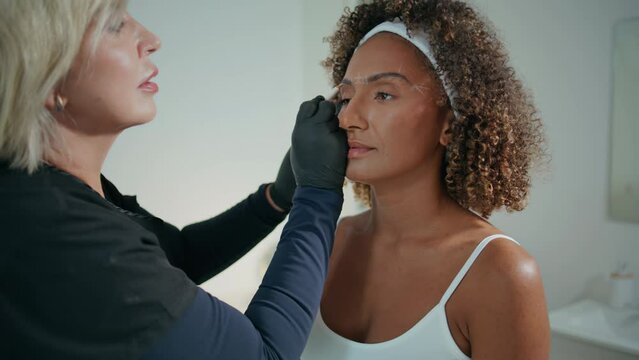 Beauty master doing brows correction closeup. Beautiful patient visiting clinic