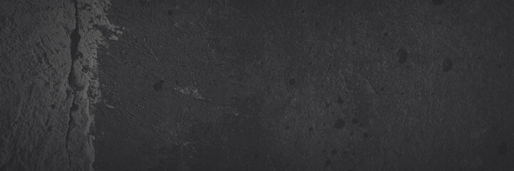 Texture of old cracked concrete wall. Rough faded dark gray concrete surface with spots, cracks, noise and grain. Dark wide panoramic background for grunge style design. Shaded texture with vignette.