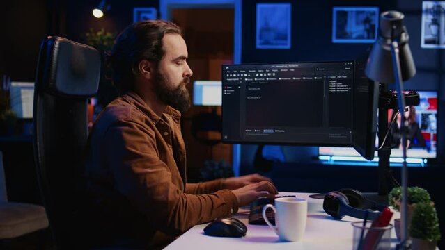 Developer overthinking solutions while doing programming during remote job shift in home office. IT admin working on computer in apartment late at night, thinking how to fix bugs, camera B