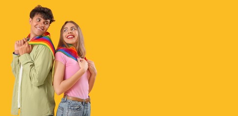 Young couple with LGBT flags on yellow background with space for text