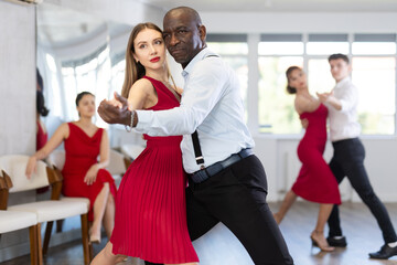 Adult man and young woman dance ballroom dance waltz in studio