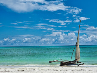 Zanzibar beach with wooden sailboat under blue sky Sun