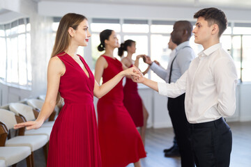 Group lesson - waltz training, male and female participants stand in pairs. Row of some dancing...
