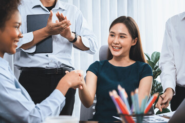 Diverse coworkers celebrate success with handshake and teamwork in corporate workplace....