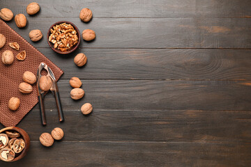 Bowls with walnuts and nutcracker on wooden background