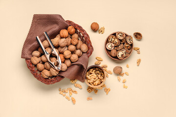 Wicker basket and bowls with walnuts on yellow background