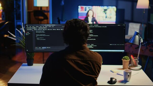 Man doing IT support job from apartment personal office drinking cup of coffee while coding. Software developer enjoying hot beverage and writing lines of code on computer, camera B