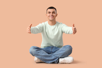 Fototapeta na wymiar Young man opening arms for hug on beige background