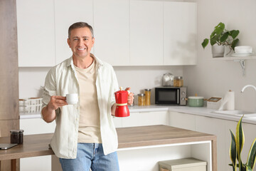 Mature man with geyser coffee maker and cup in kitchen