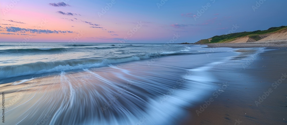 Poster waves from the ocean rolling onto the sandy beach, creating a rhythmic pattern of water movement wit