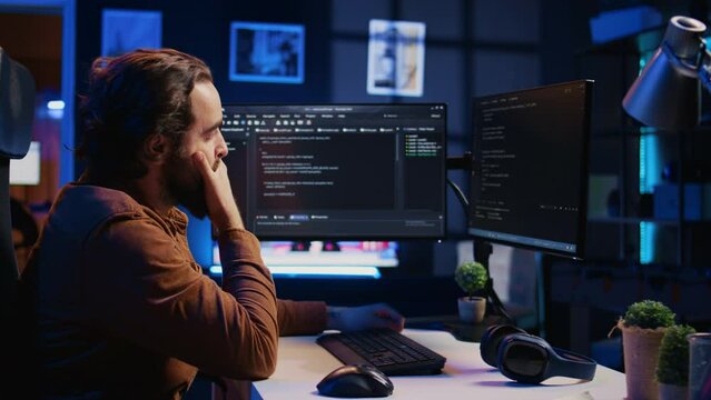 Annoyed software developer exasperated after failing to remove all bugs while coding on computer desktop. Teleworking IT specialist throwing keyboard, frustrated by script errors, camera B