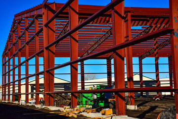 Large steel beams in use as framework for large commercial building under construction in busy industrial  area.