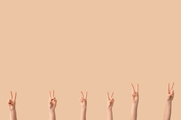Female hands showing peace gestures on beige background