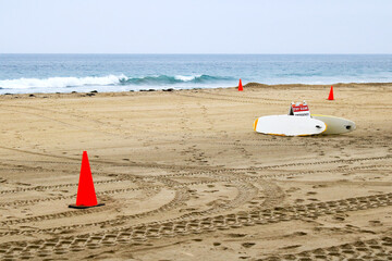 Access area to ocean for lifeguard personal marked with red cones, surfboards and folding placard...