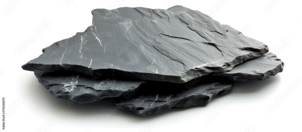 Poster a stack of black slate stones is seen precariously balanced on top of each other against an isolated