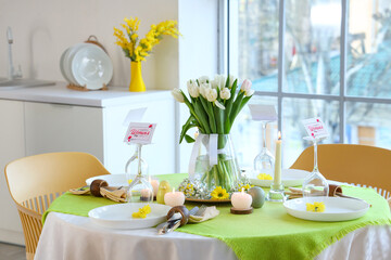 Dining table with tulip flowers and burning candles served for International Women's Day celebration