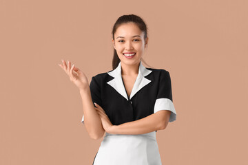 Young Asian chambermaid on brown background