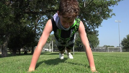 Low angle video of young athlete doing push ups then collapsing outdoors on grass - Powered by Adobe