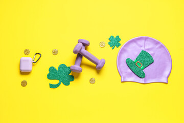 Dumbbells, swimming cap and decorations for St. Patrick's Day celebration on yellow background