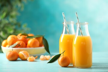 Bottles of fresh tangerine juice on blue wooden background. Space for text
