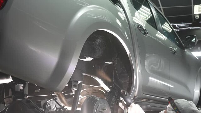 The master sprays an anti-corrosion compound on the bottom of the car. 