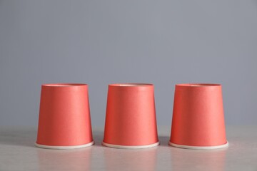 Shell game. Three red cups on light table