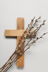 Wooden cross and willow branches on light grey background, top view. Easter attributes