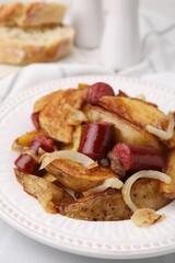 Delicious baked potato with thin dry smoked sausages and onion on table, closeup