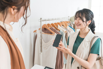 スマホ・スマホ決済・オンライン決済で買い物をする女性とショップ店員
