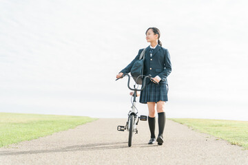 Obraz premium 自転車で通学・登校・下校する制服姿の中学生・高校生（夢・希望・進路・道・将来・未来・青春・歩く） 