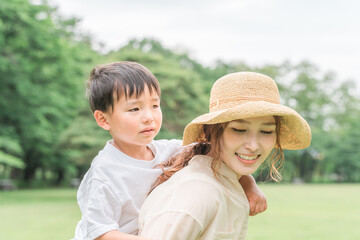 公園で泣く子供をおんぶしてあやすママ・母親

