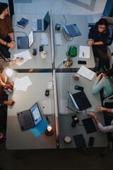An overhead view of a diverse, multigenerational business team discussing strategies during an...