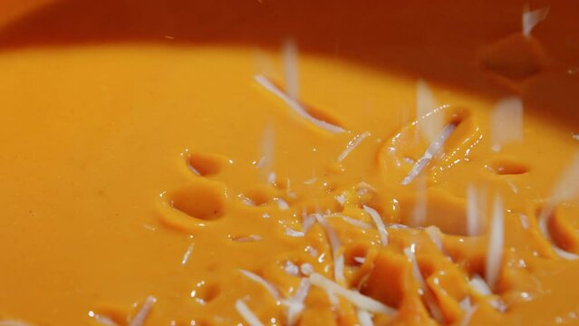 Pouring shredded cheese into tomato soup