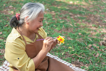Elderly woman doing activities in the park Use a paintbrush to paint pottery. learn art to treat...