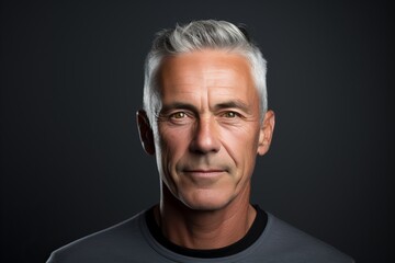 Portrait of a handsome mature man with grey hair against black background - obrazy, fototapety, plakaty