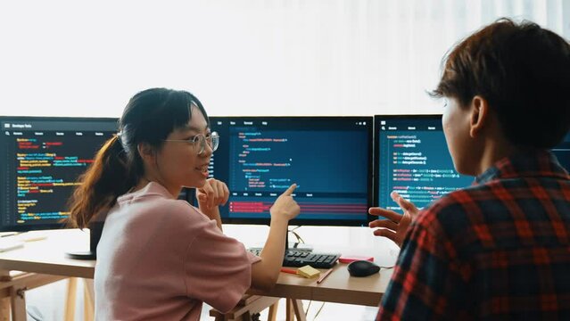 Slow motion back end software developer engineer for computer programming working together on debugging writing computing code, solving complex algorithms display on monitor in office. Burgeoning