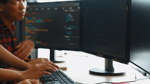 Slow motion back end software developer engineer for computer programming working together on debugging writing computing code, solving complex algorithms display on monitor in office. Burgeoning