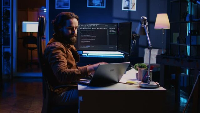 Developer writing lines of code on multimonitor PC setup during remote job shift. IT expert doing multitasking in neon lit home office, listening music, drinking coffee, camera B