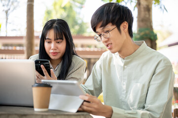 Obraz premium Two Asian male and female friends or colleagues are collaborating on work together.