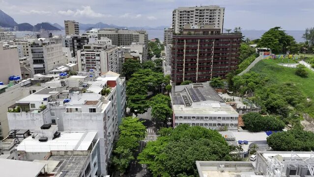 Aerial shot drone flies low along tree-lined street between Ipanema and Copacabana with hotels and new construction