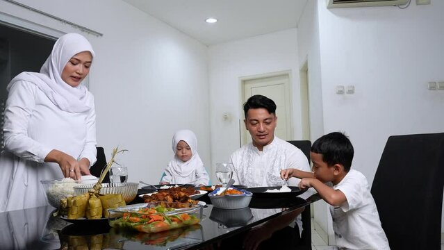Happy family eating together in the dining room during ied mubarak - lebaran celebration