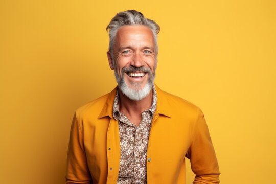 Portrait Of A Happy Senior Man Laughing And Looking At Camera Over Yellow Background