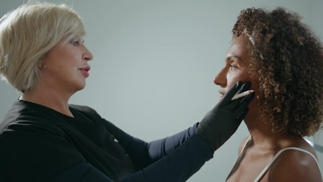 Cosmetologist consulting woman client in salon closeup. Doctor examine face skin